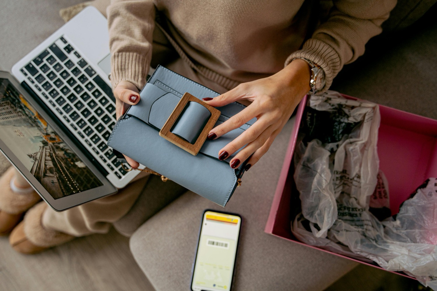 A shopper unpacking an order at home with a laptop and phone beside her