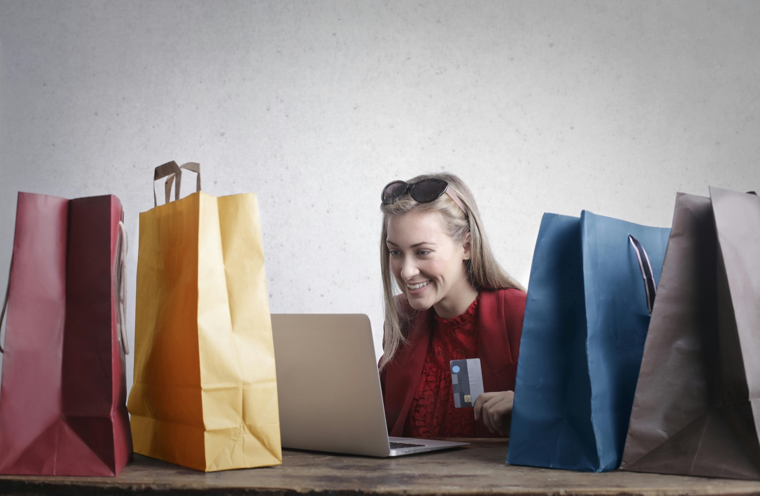 A shopper comparing products on a laptop surrounded by shopping bags
